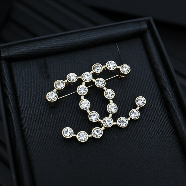 DOUBLE C LETTER BROOCH IN GOLD METAL WITH CRYSTALS AROUND LOGO