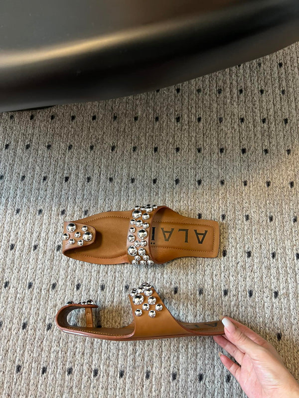 ALAIA FOLDED FLAT MULES WITH SPHERES ON COPPER BROWN CALFSKIN