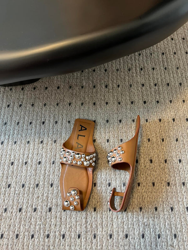 ALAIA FOLDED FLAT MULES WITH SPHERES ON COPPER BROWN CALFSKIN