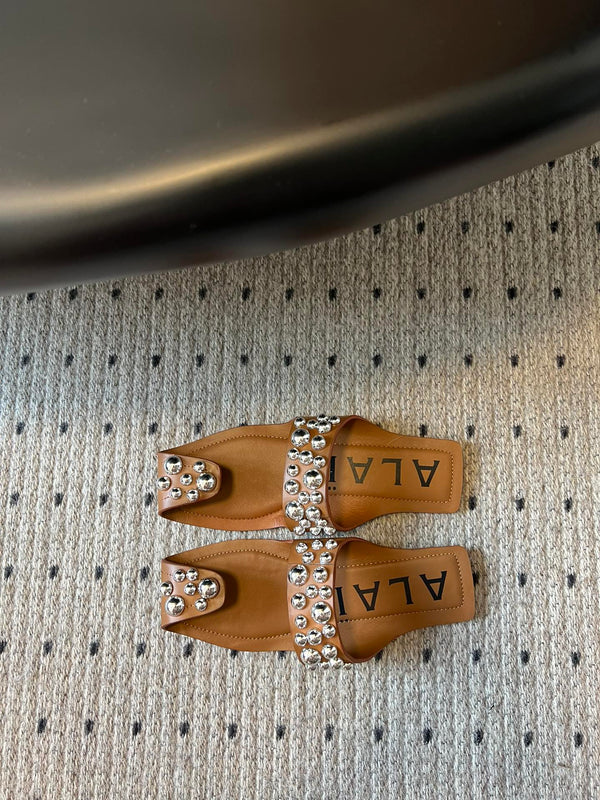 ALAIA FOLDED FLAT MULES WITH SPHERES ON COPPER BROWN CALFSKIN